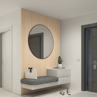 A modern entryway features the Artika Panolok 30.67 ft wall panel kit (pack of 8) with an oak finish slatwall, a round mirror, floating gray cushioned bench, white drawer, potted plant, beige tote bag, and black-and-white sneakers.