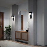 A modern hallway with an arched mirror, a rattan-front console table, two wall sconces, a potted plant, and a wooden door. The space features neutral colors and minimalist decor.