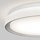 A modern, circular ceiling light fixture with a smooth, white finish emitting a soft, even glow. The image shows a close-up, angled view against a light gray ceiling.