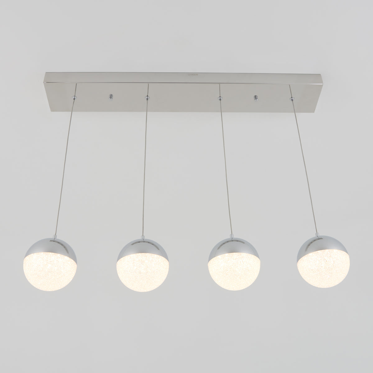 The Artika Sparkle 4-light LED pendant features four frosted glass globes suspended by slim wires from a sleek rectangular metallic base, creating a modern statement for any space.