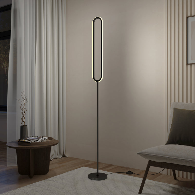 The Artika Leni dimmable LED modern floor lamp, featuring an oval design and black stand, emits soft light in a minimalist living room beside a small round table, light curtains, and a cushioned chair.