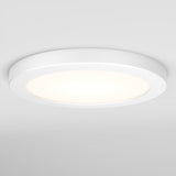 A round, white ceiling light fixture with a modern, minimalistic design is illuminated against a plain white ceiling.
