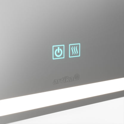 A close-up of the touch screen panel on the Artika Aurea anti fog LED wall mirror shows two illuminated icons—a power symbol and wavy lines—above the Artika logo, with a reflective surface and white horizontal light beneath.