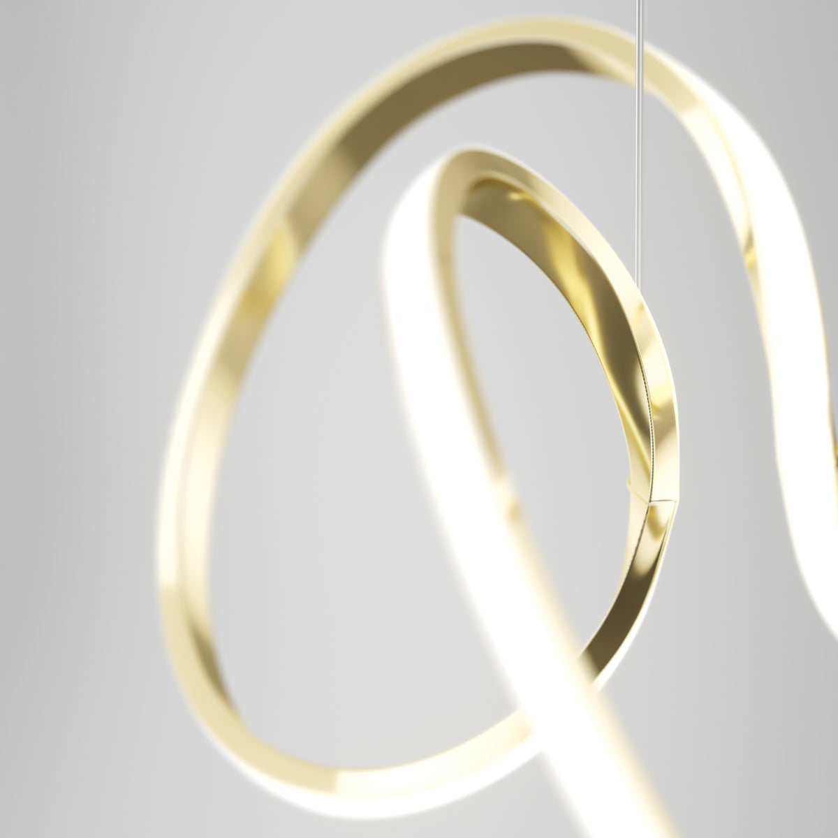 The Artika Swirl LED pendant light showcases contemporary style with intertwined gold and white illuminated loops, set against a blurred light gray background.