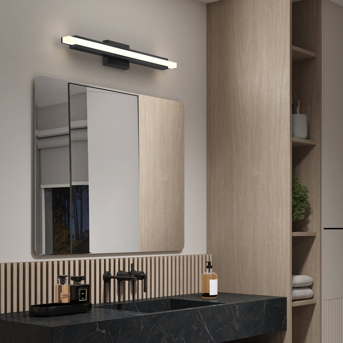 Modern bathroom with light wood paneling, a black marble countertop, a square mirror, a rectangular LED wall light above the mirror, black faucet fixtures, a soap dispenser, and shelves with a plant.