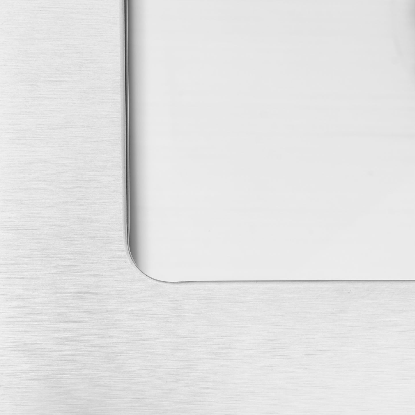 Close-up of the Artika Plaza Bar Single Bowl Sink’s brushed metal surface with a rounded rectangular cutout, showing a smooth, white reflective area inside.