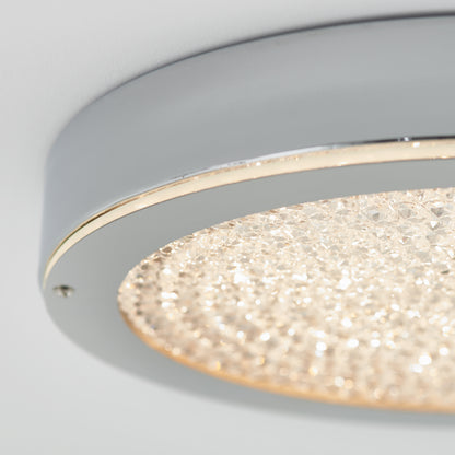 Close-up of the Artika Glitter LED flush mount, featuring a metallic silver edge and a crystal-like textured surface that emits a warm, shimmering glow.