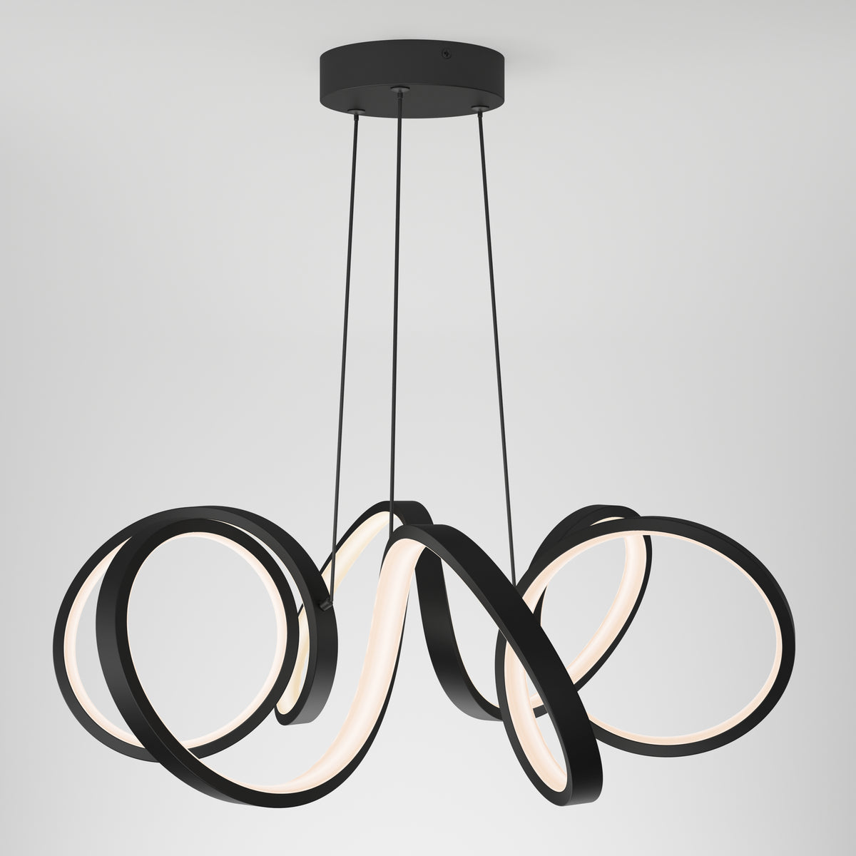 The Artika Swirl Ribbon LED pendant light features three intertwined black LED rings suspended by cords, creating a modern, sculptural look against a plain white background.