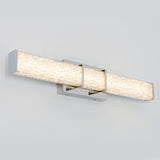 A modern, rectangular wall-mounted light fixture with two long, textured, frosted glass bars and a chrome finish, emitting a bright, even glow against a light gray wall.