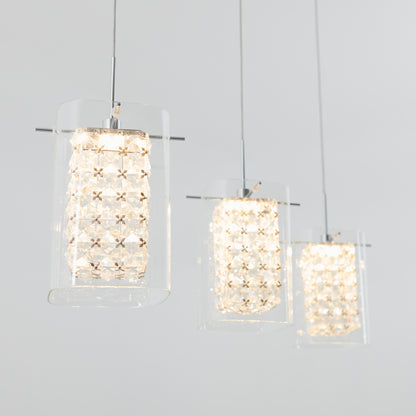 The Artika Crystal Cube 3-light LED pendant light features three modern pendants with glass and crystal-like cylindrical shades, casting a soft white glow against a light gray background.