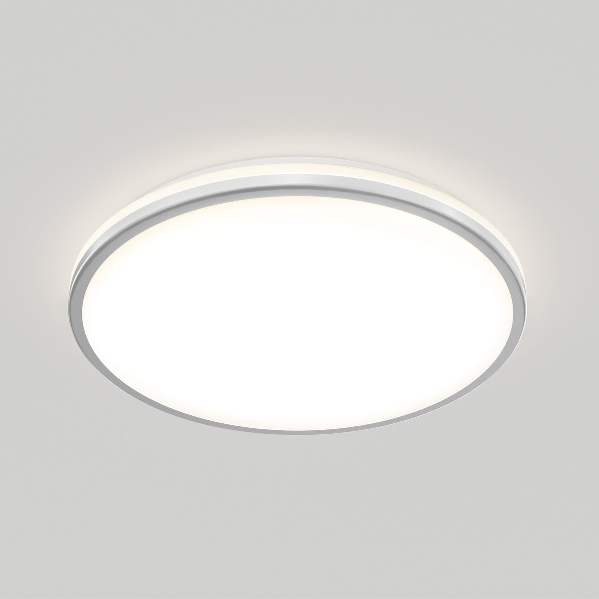 A round, white ceiling light fixture is mounted on a plain light gray ceiling, emitting a soft, even glow.