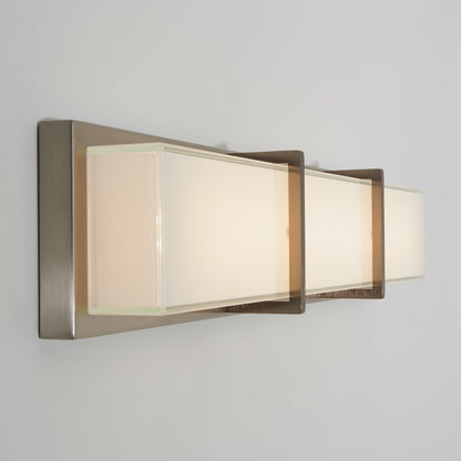 The Artika Subway LED bathroom vanity light features three rectangular frosted glass shades and a sleek brushed metal base, mounted horizontally on a light-colored wall.