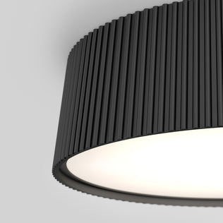 A close-up of the Artika Groove 13 in. LED modern flush mount light features a black, vertically ribbed shade with a bright white interior, set against a plain light gray background. 5 CCT color temperatures are available.
