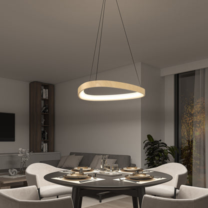 A modern dining room with a round black table for four, beige chairs, a gray sofa, shelves, and a plant is illuminated by the Artika Bjorn modern LED pendant light 5 CCT. A window shows trees outside at dusk.