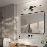 A modern bathroom with a rectangular mirror, a wall-mounted black faucet, a square white sink, and a wooden vanity. Above the mirror is a sleek, horizontal light fixture. Gray tiles and a towel are visible in the background.