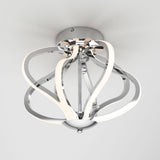 A modern ceiling light fixture with curved chrome arms and integrated LED strips, mounted on a white ceiling. The design is sleek and contemporary, resembling an abstract flower or swirling ribbons.