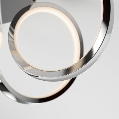 Close-up of the Swirl Ribbon LED pendant light by Artika, showcasing two intertwined chrome rings with integrated LEDs. The modern, minimalist design creates an elegant statement against a plain light gray background.