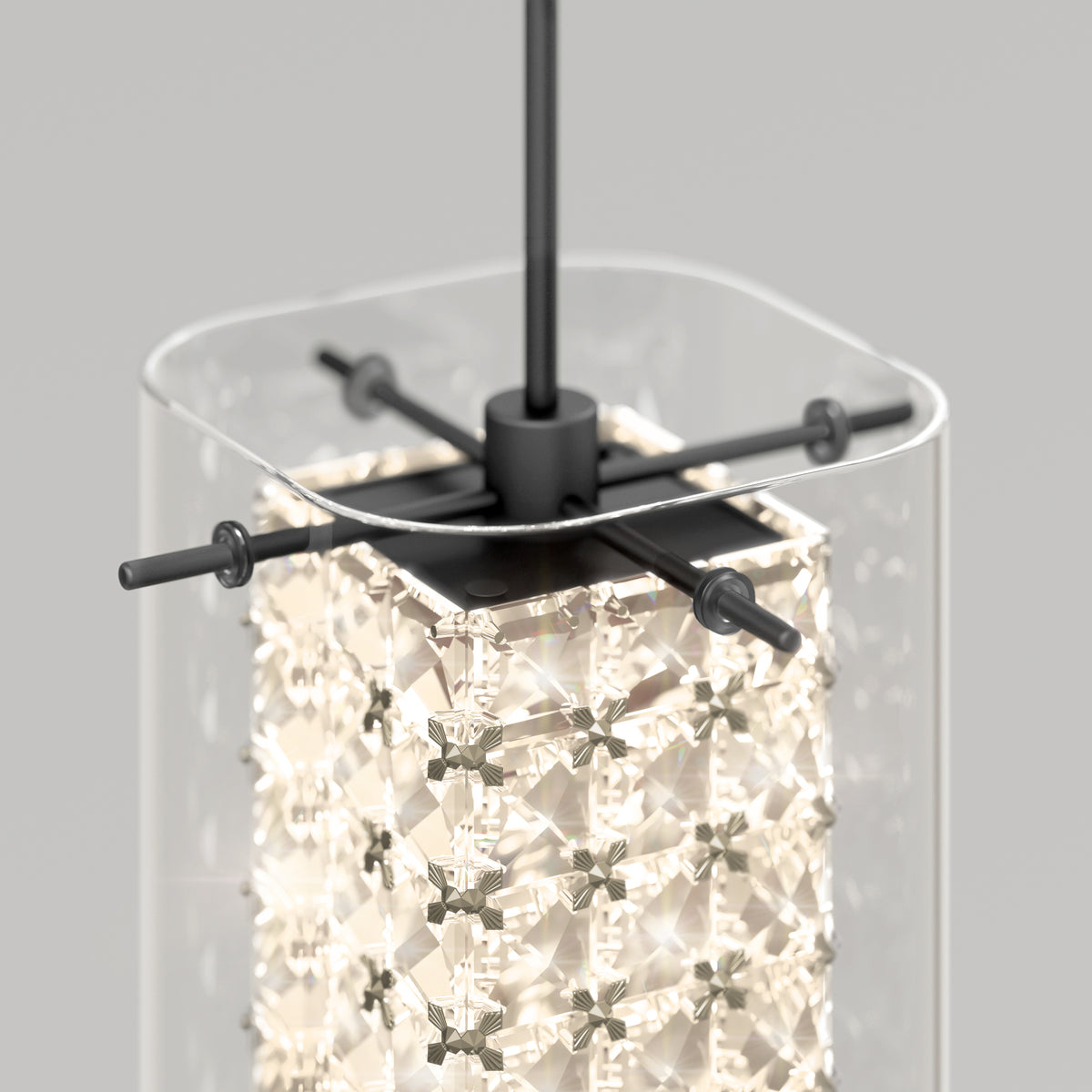 A close-up of a modern pendant light featuring a clear rectangular glass shade, a square metal frame, and an illuminated inner crystal structure with intricate geometric patterns.