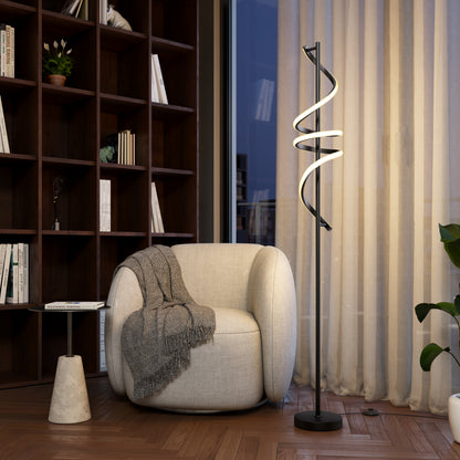 A cozy, rounded white armchair with a gray blanket sits next to the Artika Coda modern LED floor lamp 5CCT in a stylish room featuring wood floors, built-in bookshelves, and large windows with sheer curtains.