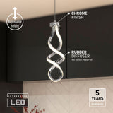 A modern pendant light with a twisted design hangs from the ceiling. It features a chrome finish, rubber diffuser, and integrated LED. Text highlights adjustable height and a 5-year warranty. The light is above a tiled kitchen wall.