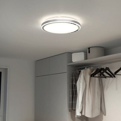 The Artika Altitude 15 in. LED modern flush mount light brightens a minimalist closet with light gray cabinets, hanging coats, empty hangers, and storage boxes on the upper shelf.