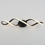 A modern wall light fixture with two intertwined, wave-like LED strips—one illuminated white, one dark—mounted on a round black base against a plain gray background.
