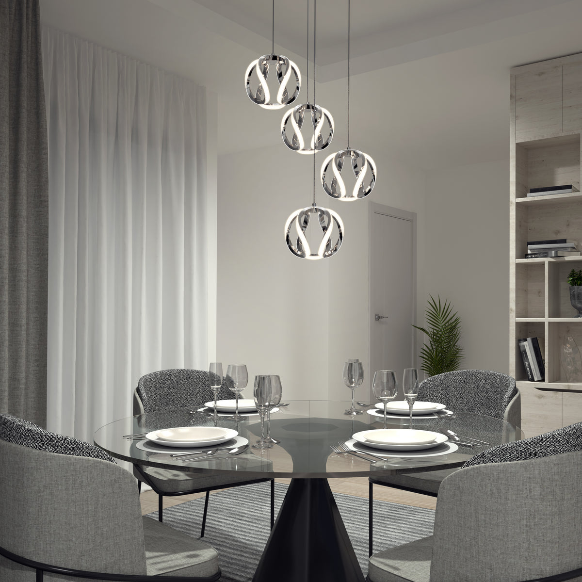 A modern dining room with a round glass table set for four, gray upholstered chairs, contemporary pendant lights above, sheer curtains, and a bookshelf with decor and a potted plant in the background.