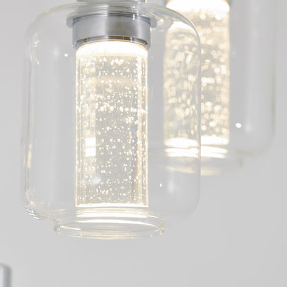 Close-up of the Artika Champagne Globe 4-light LED pendant, featuring clear cylindrical glass shades with bubble-filled rods emitting bright white light. Minimalist out-of-focus background enhances the modern design.