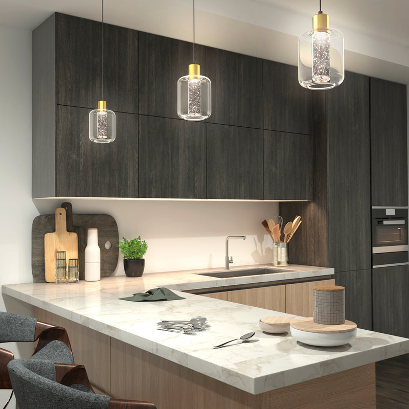 Modern kitchen features dark wood cabinets, a marble island with two chairs, and various items like cutting boards, utensils, plants, and plates. Three Artika Champagne Globe modern LED pendant lights hang above the island.