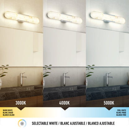 The Artika Selena 3 CCT LED bathroom vanity light is displayed above a sink and dark countertop, showing three color temperatures—3000K (warm), 4000K (neutral), 5000K (cool)—with multilingual labels below.