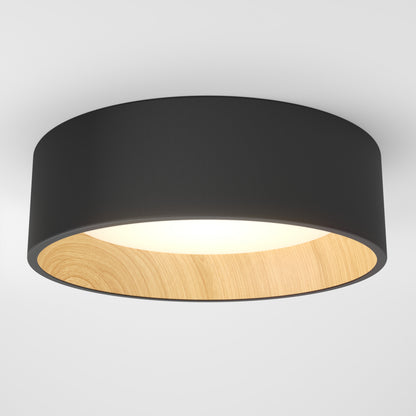 The Artika Alton LED flush mount features a black outer rim, light wood inner rim, and white diffused surface. This dimmable ceiling fixture offers stylish modern lighting when mounted on a white ceiling.