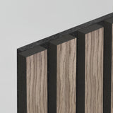 A close-up view of a decorative wall panel featuring alternating vertical slats of light wood grain and matte black surfaces, shown against a plain light background.