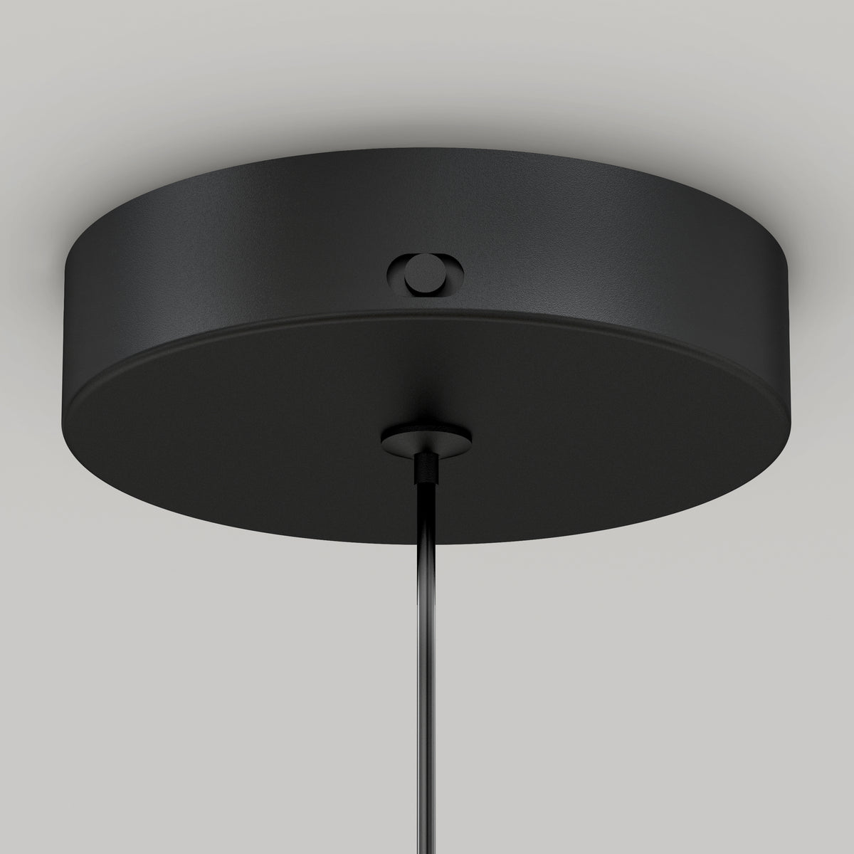Close-up view of a round, black ceiling canopy with a smooth finish, attached to the ceiling and holding a single cord hanging down from its center.