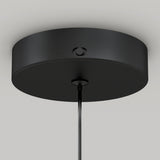 Close-up view of a round, black ceiling canopy with a smooth finish, attached to the ceiling and holding a single cord hanging down from its center.