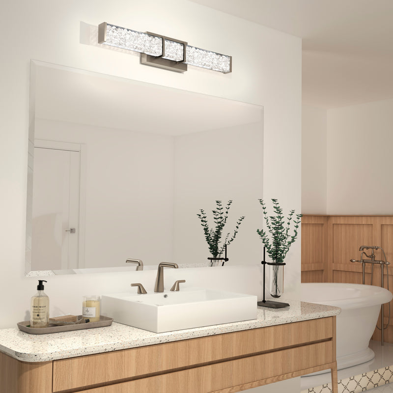 Modern bathroom with a large mirror, vessel sink, dual faucets, plants, tub, and an Artika Royale 27-in LED Vanity Light Bar above the mirror.