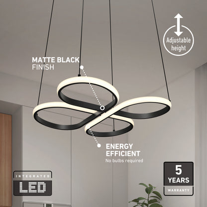 Modern LED pendant light with a matte black finish, shaped in intertwined loops, hanging from the ceiling. Text highlights adjustable height, energy efficiency, integrated LED, and a 5-year warranty. Plant and kitchen in background.