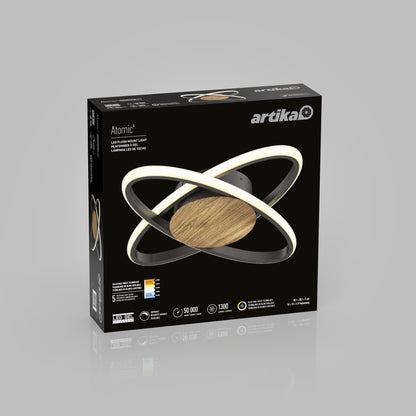 A black box displays the Artika Atomic 15 in. LED flush mount light 5 CCT, featuring a modern ring-shaped design. The packaging highlights dimmable lighting, energy savings, and wood-style accents.