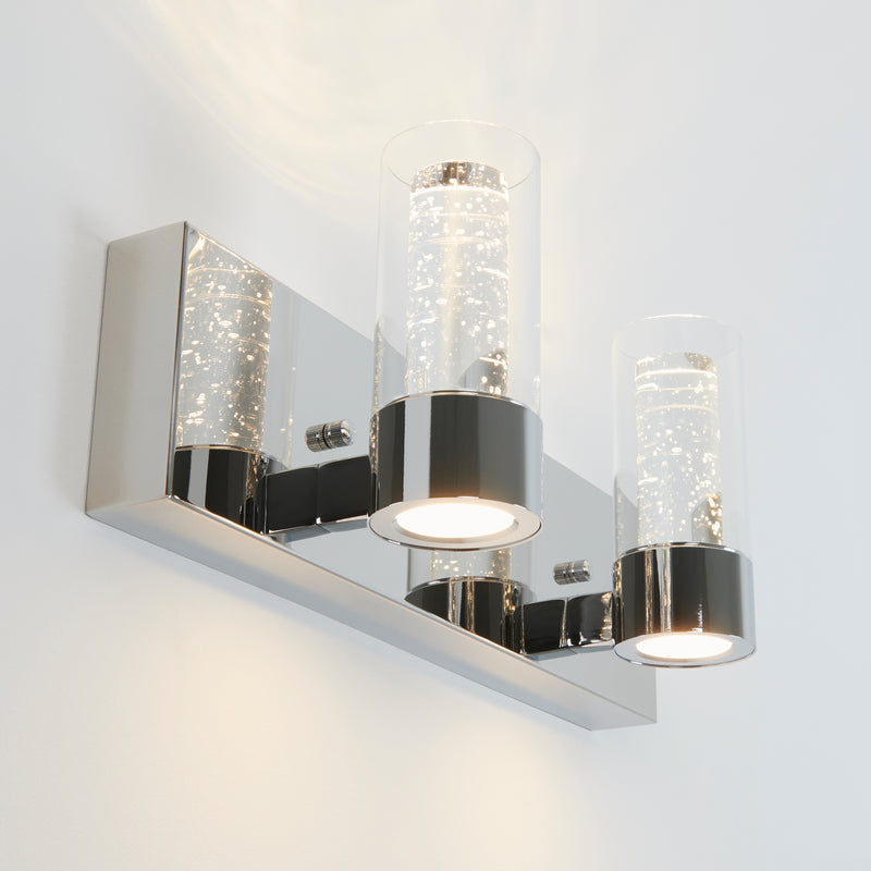 The Artika Ratio 2-light LED bathroom vanity light features a modern wall-mounted design with a rectangular chrome base and two bubble-detailed glass shades that emit bright, white light.