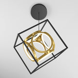 A modern ceiling light fixture featuring a black cube frame with gold geometric rings and circular LED lights suspended in the center, set against a white background.