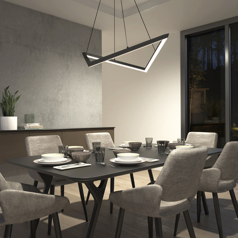 A modern dining room features a black table set for six with light gray cushioned chairs. Above, the Artika Artemis LED pendant light 3 CCT hangs. A large window and potted plant complete the scene.