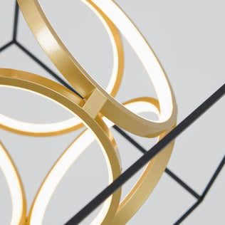 Close-up of Artikas Luxury LED pendant light, with intersecting gold metal rings and integrated LEDs, set against a plain light gray background. Black structural lines accent the composition.