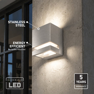 Square Valor Square LED indoor-outdoor wall light on concrete, with labels noting its stainless steel construction and five-year warranty.