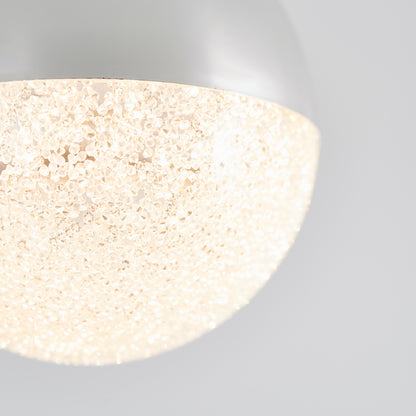 Close-up of the Artika Glitzer LED pendant light, featuring a textured, translucent cover that emits a warm, sparkling glow against a plain white background.