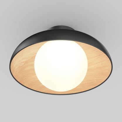 The Artika Boden LED flush mount light 5 CCT features a modern design with a black outer rim, wooden inner lining, and glowing white bulb at the center, displayed against a plain gray background.