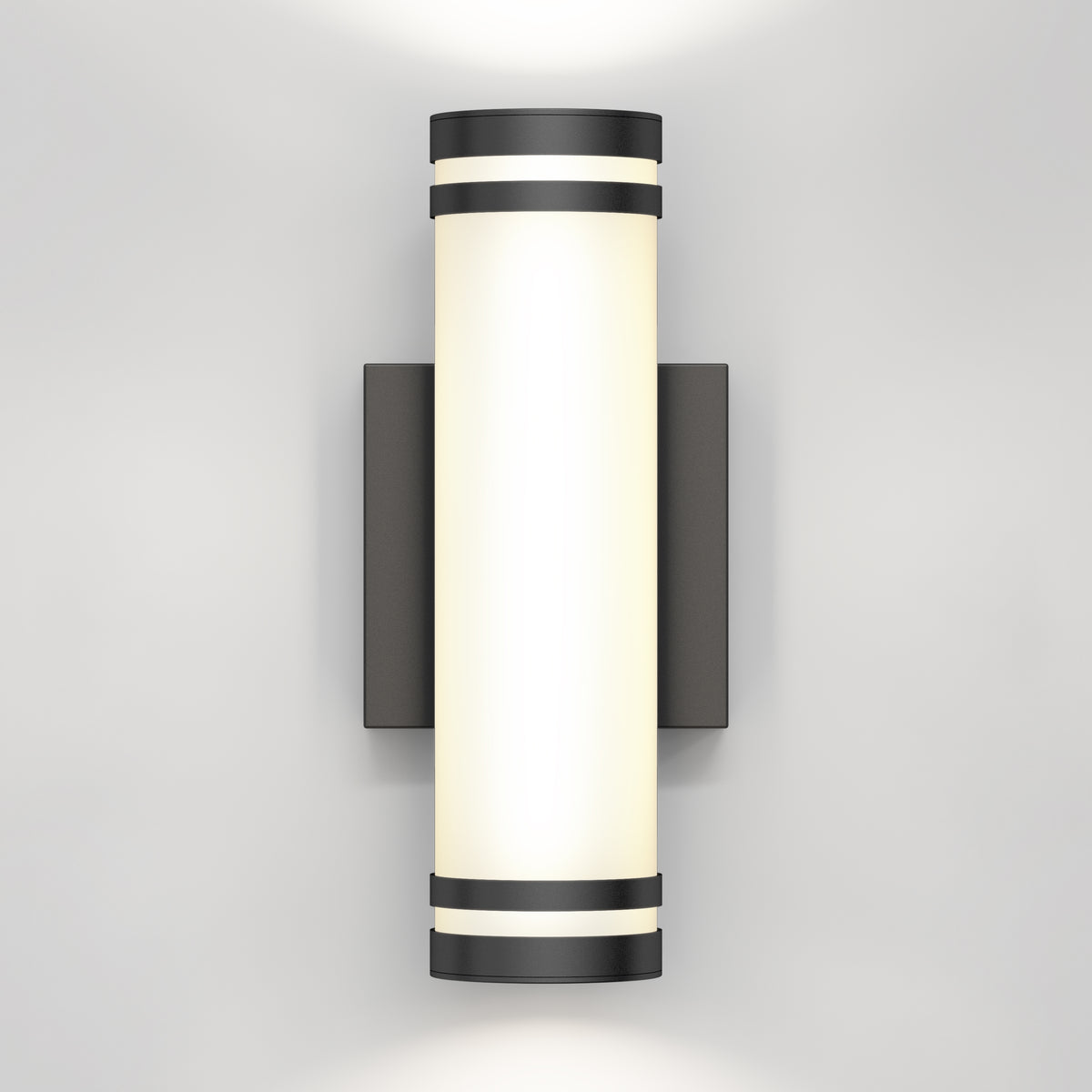 A modern wall-mounted cylindrical light fixture with black accents at the top and bottom, emitting a soft white glow against a plain light gray wall.