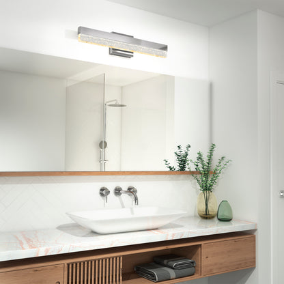 Modern bathroom featuring a rectangular mirror, the Artika Essence Bubble Bar LED vanity light above, vessel sink on marble countertop, wood vanity with towels below, and green vases with foliage. Shower is reflected in the mirror.