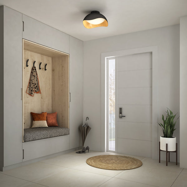 A modern entryway features a built-in wooden bench, cushions, hanging hooks with a jacket and scarf, umbrella holder, potted plant, round doormat, white front door letting in natural light, and an Adara 15 in. LED flush mount light by Artika-CAN-dev.