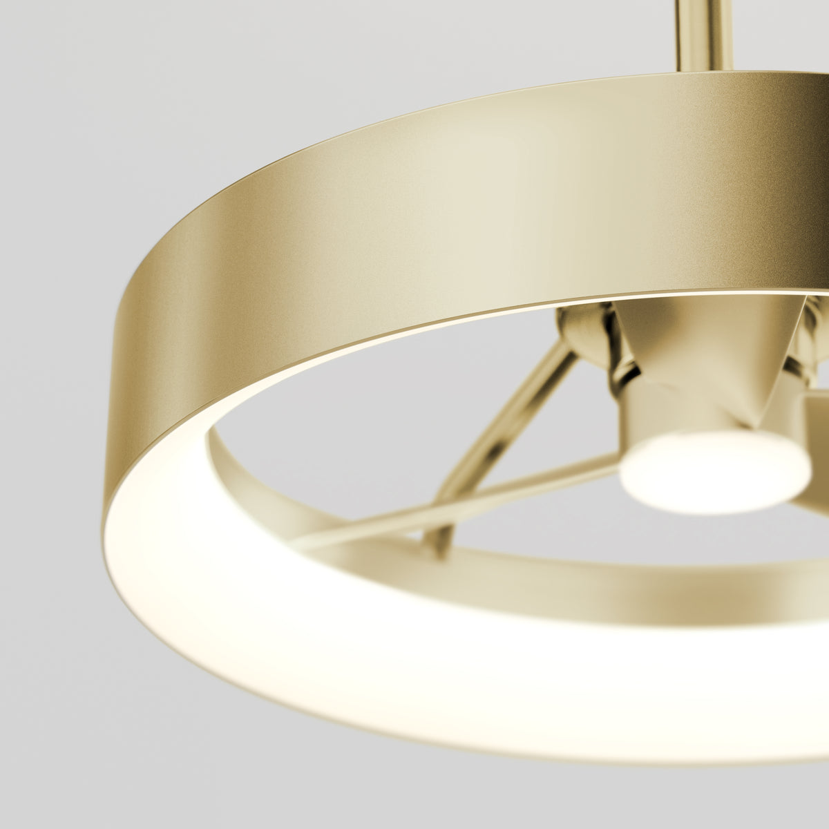 Close-up of a modern, circular, gold-colored ceiling light fixture with a glowing white ring and metallic supports, set against a plain light background.