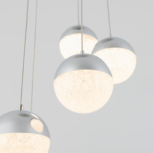 Five contemporary Sparkle LED pendant lights by Artika, featuring textured frosted bottoms and sleek silver tops, are suspended from the ceiling against a simple light backdrop.