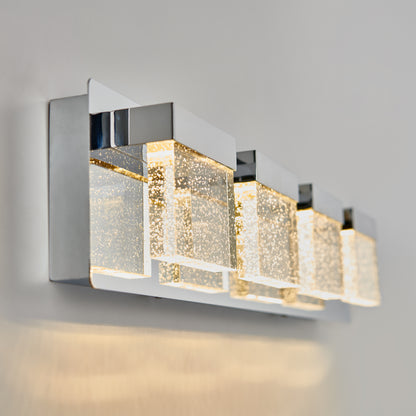 The Artika Bubble Cube 4-light LED bathroom vanity light features four rectangular, bubble-filled glass lights with chrome accents, mounted on a light wall and casting a soft glow.
